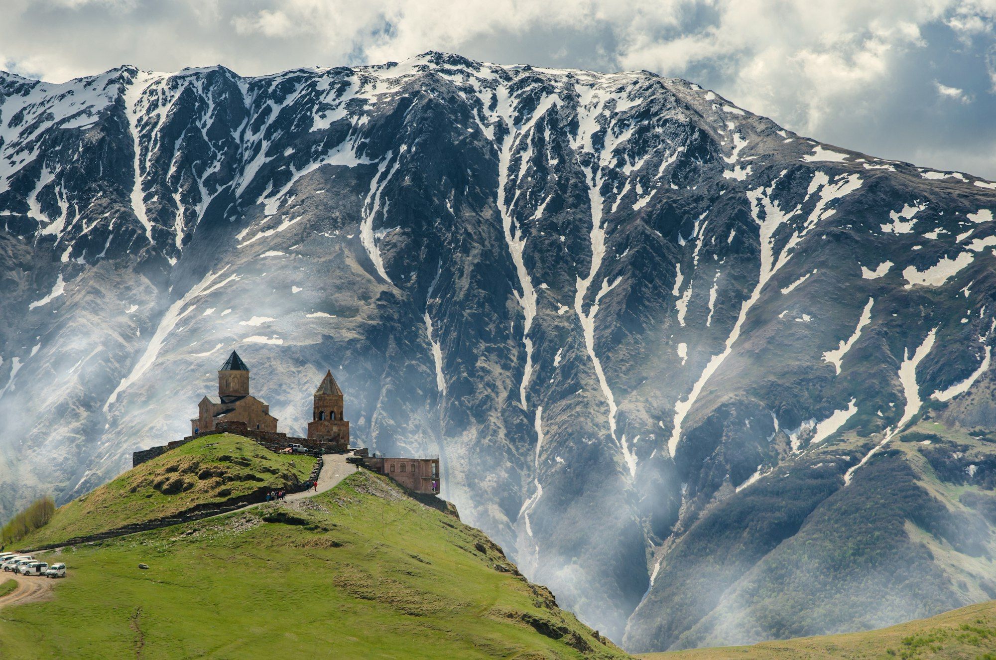 Gergeti Trinity Church on its green hill below the snows of Kazbegi at first light