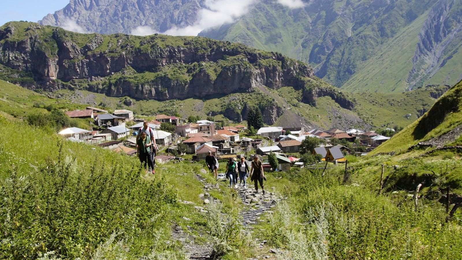 Walkers climbing the stone path above Stepantsminda village in Kazbegi